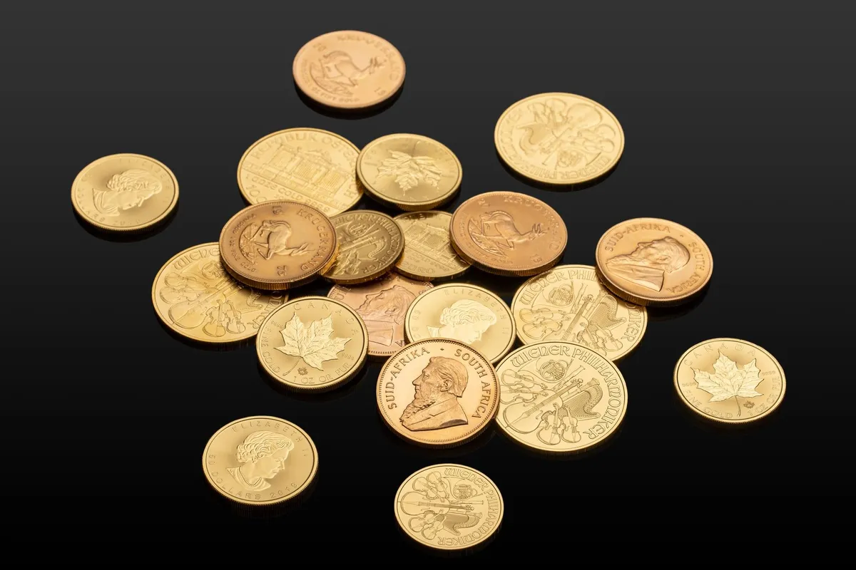 Close-up of various international gold coins on a reflective surface, highlighting their value for sellers.