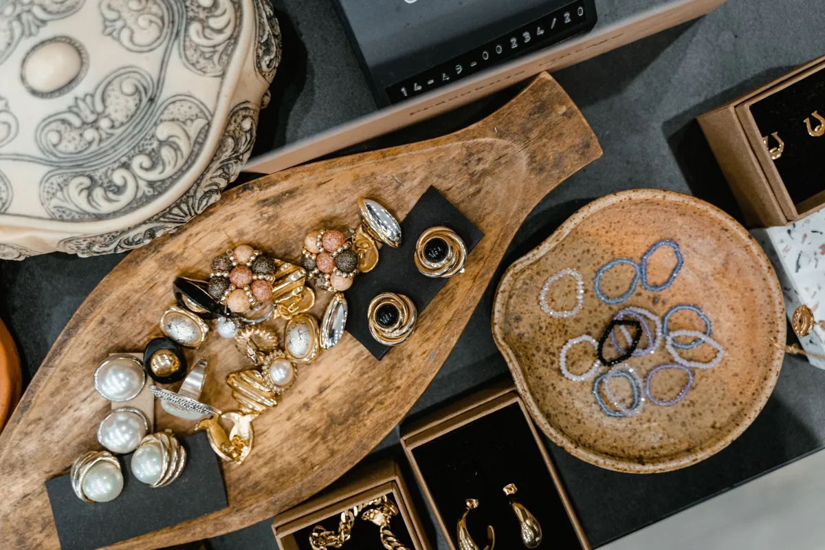 Assorted vintage rings and bracelets displayed in a wooden tray and ceramic dish, highlighting jewelry market.