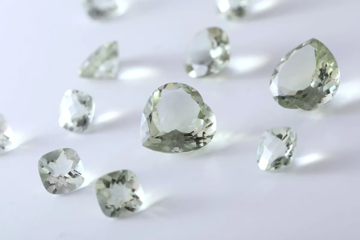 Close-up of various green gemstones reflecting on a white surface, hinting at future jewelry trends.