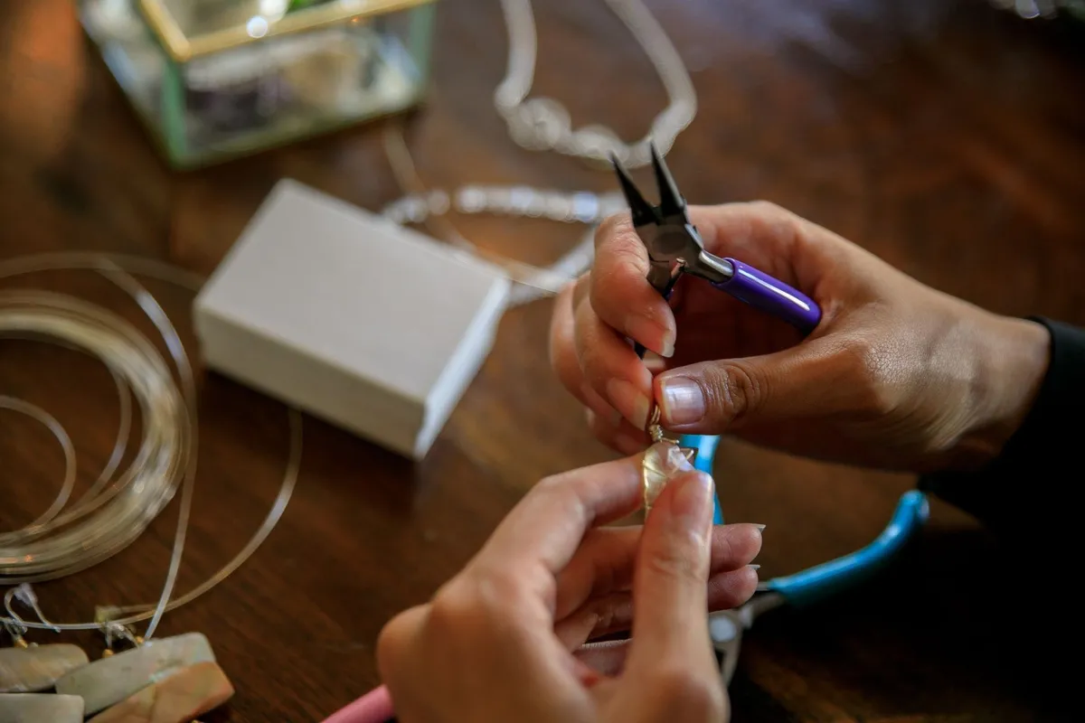 A close-up of hands using pliers to craft silver jewelry, highlighting the artistry behind its value.